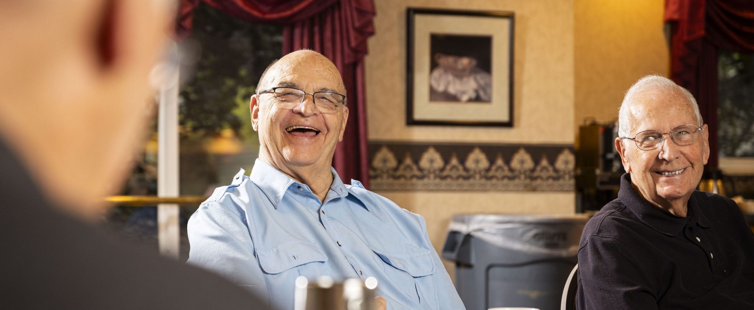 Friends share a laugh at Willow Brook in Delaware, Ohio, used as a full-width background image on the Lifestyle page of this senior living community.